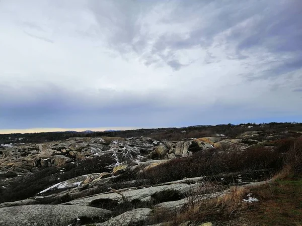 Paisaje de rocas cubiertas de ramas bajo un cielo nublado durante la noche en Rakke en Noruega — Foto de Stock