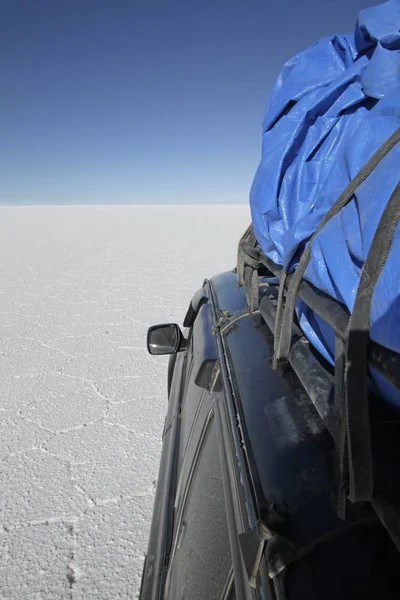 Colpo verticale di un'auto su un campo vuoto sotto un cielo blu — Foto Stock