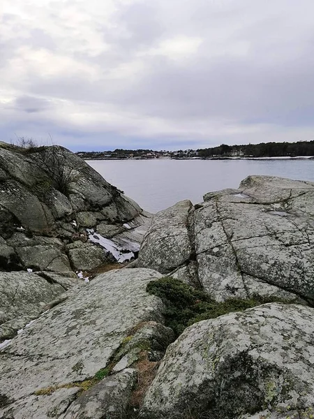 Vertikal bild av klippor omgivna av floden under en molnig himmel i Norge — Stockfoto