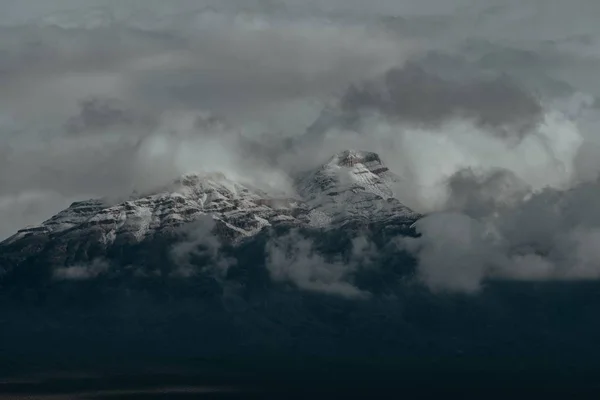 Picchi innevati delle montagne coperte dal cielo nuvoloso scuro — Foto Stock