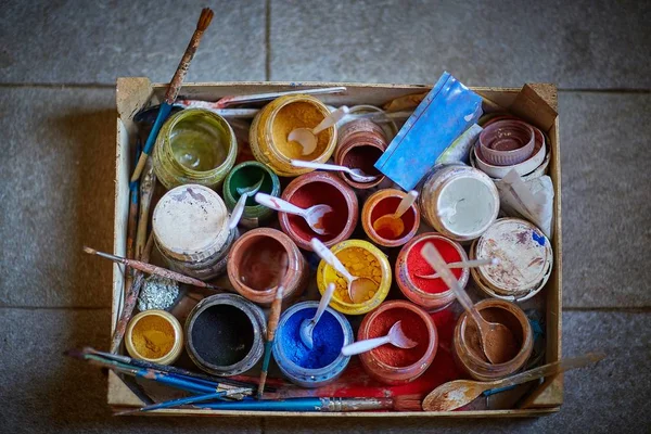 콘 크리 이트 표면에는 다채 로운 페인트 색소와 솔 이 가득 들어 있는 상자 — 스톡 사진