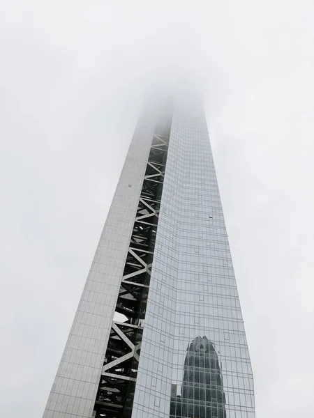 Låg vinkel skott av en hög byggnad med dimma som täcker den övre delen av det — Stockfoto
