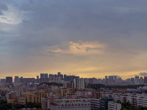 Με θέα σε μια σύγχρονη και πολυσύχναστη πόλη με σκούρο μπλε ουρανό και σύννεφα κατά τη διάρκεια του ηλιοβασιλέματος — Φωτογραφία Αρχείου