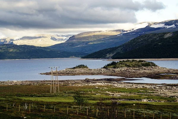 Paysage d'un lac entouré de montagnes verdoyantes sous un ciel nuageux en Norvège — Photo