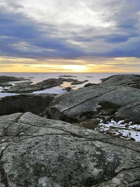 Verticaal beeld van rotsen omringd door de zee tijdens de zonsondergang in Rakke in Noorwegen — Stockfoto
