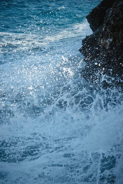 Vertical shot of the waves of the ocean and the white foam formed as a result — Stock Photo, Image