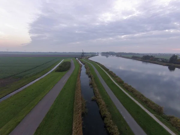 Drone zicht op een Nederlands landschap onder een bewolkte lucht met wolken die overdag op het water reflecteren — Stockfoto