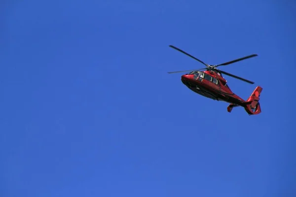 Laaghoekige opname van een rode helikopter met een blauwe lucht op de achtergrond — Stockfoto