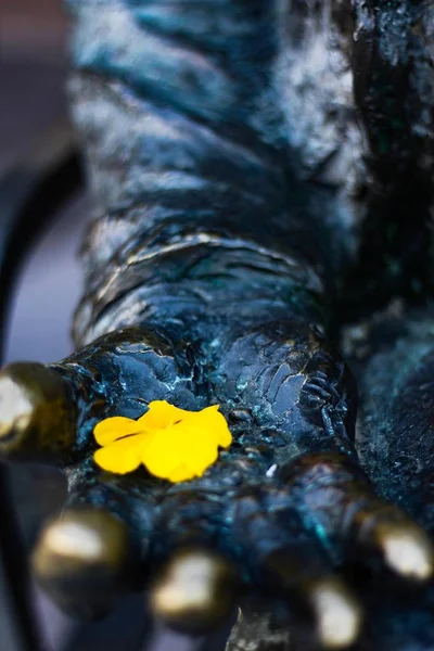 Photo de clôture verticale d'un pétales jaunes d'une fleur sur une statue de pierre — Photo