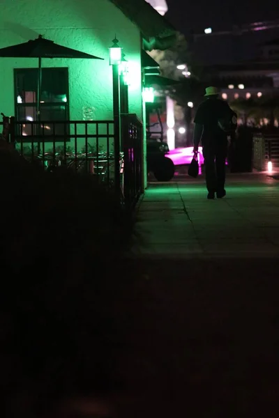 Pionowe ujęcie mężczyzny przechodzącego nocą przez miasto. — Zdjęcie stockowe