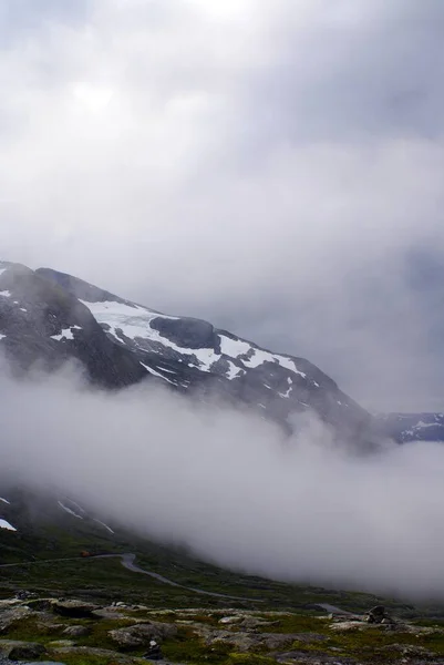 Prachtig landschap van hoge rotsachtige bergen bedekt met sneeuw omhuld door mist in Noorwegen — Stockfoto