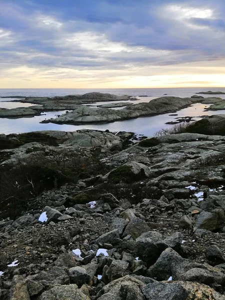 Vertikal bild av klippor omgivna av havet under solnedgången i Rakke i Norge — Stockfoto