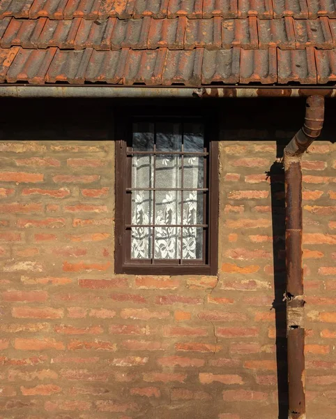 Närbild skott av fönstret i en gammal byggnad gjord av tegel med ett rostigt tak på en solig dag — Stockfoto