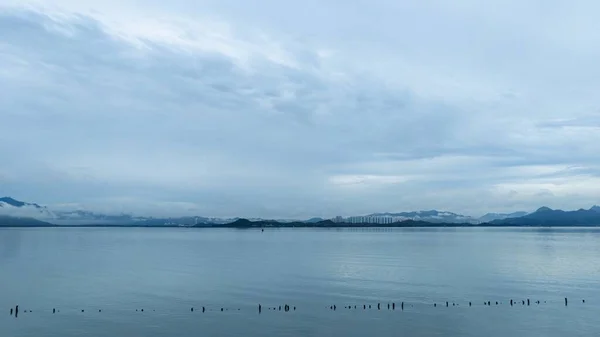Bred bild av ett lugnt hav med utsikt över bergen en molnig dag — Stockfoto