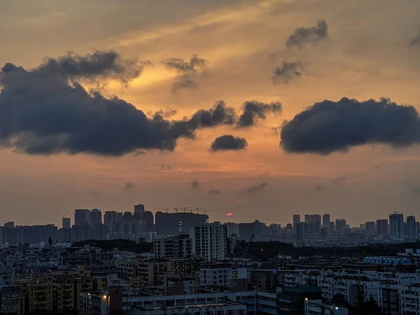 Vue d'ensemble d'une ville moderne et animée avec des nuages sombres et un ciel orange — Photo