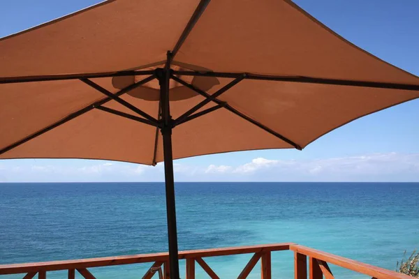 Bruine paraplu op het strand tegenover de oceaan — Stockfoto