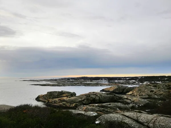 Norveç 'te gün batımında bulutlu bir gökyüzünün altında dallarla çevrili bir deniz. — Stok fotoğraf