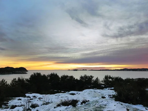 노르웨이의해 가 지는 동안 눈덮인 푸른 초목으로 둘러싸인 바 다 — 스톡 사진