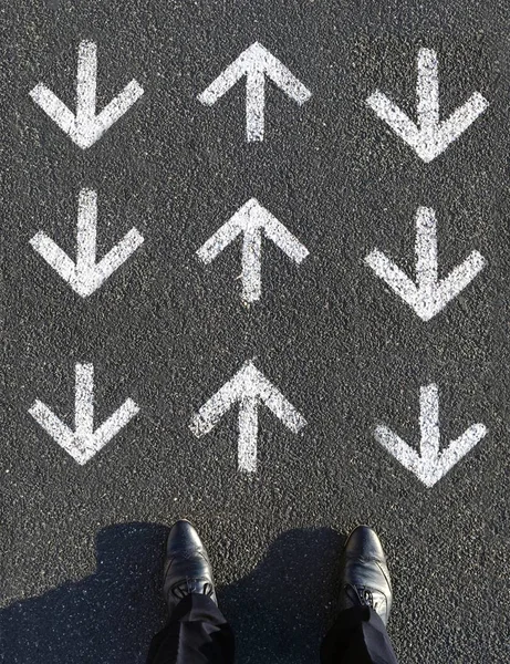 Een mannetje dat voor de pijl op de asfaltweg staat en naar boven en naar beneden wijst — Stockfoto