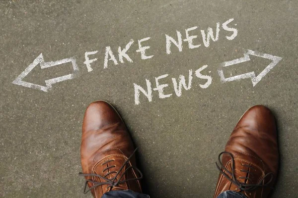 Hög vinkel skott av nyheter och falska nyheter markerade med motsatta riktningar på marken — Stockfoto