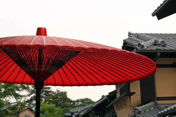 Paraguas rojo rodeado de árboles y un edificio durante el día —  Fotos de Stock