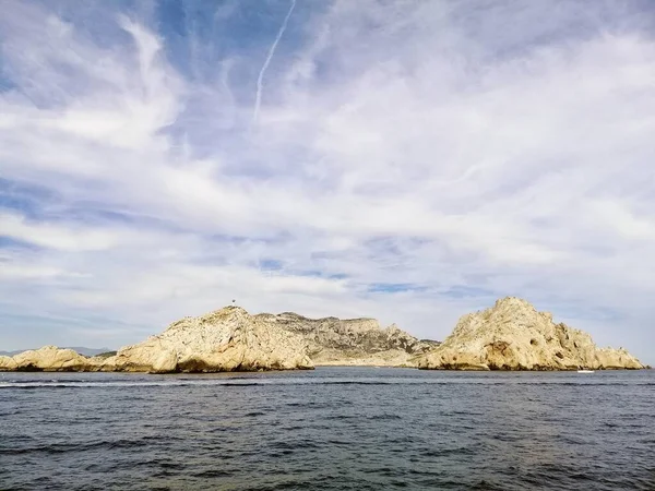 Massif des Calanques otoczony morzem pod chmurnym niebem i słońcem w Marsylii we Francji — Zdjęcie stockowe