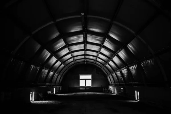 Greyscale tiro de uma sala de túnel escuro com uma janela — Fotografia de Stock