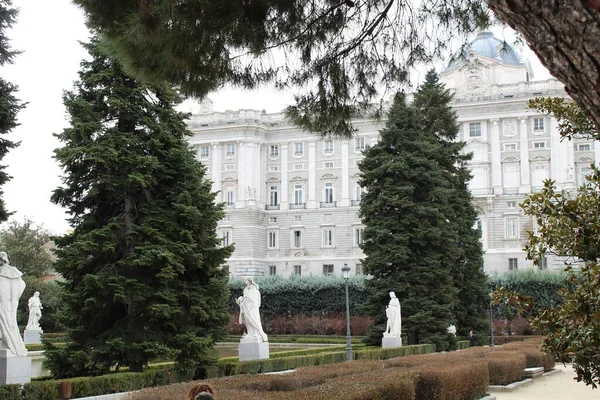 Koninklijk Paleis van Madrid omgeven door groen onder een bewolkte hemel in Madrid in Spanje — Stockfoto