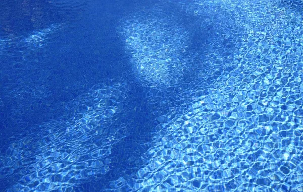Κυματισμοί στην επιφάνεια του γλυκού καθαρού νερού μιας εξωτερικής πισίνας σε μια ηλιόλουστη μέρα — Φωτογραφία Αρχείου
