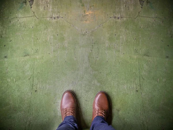 Foto de ángulo alto de una persona con zapatos marrones en una superficie verde envejecida — Foto de Stock