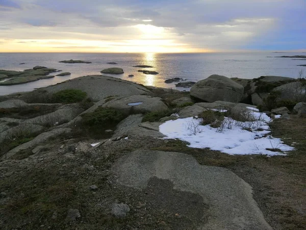 Zee omgeven door rotsen bedekt met takken onder een bewolkte hemel tijdens de zonsondergang in Noorwegen — Stockfoto