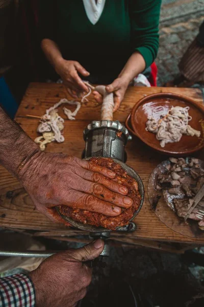 A high angle view of people grinding meat for a kielbasa with an old fashioned grinder on the table