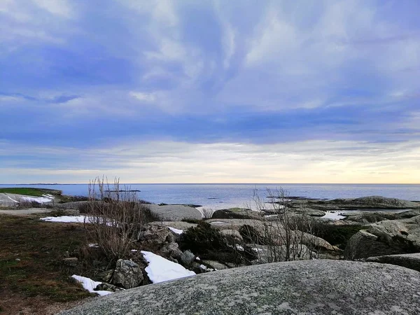 Norveç 'te gün batımında bulutlu bir gökyüzünün altında dallarla çevrili bir deniz. — Stok fotoğraf