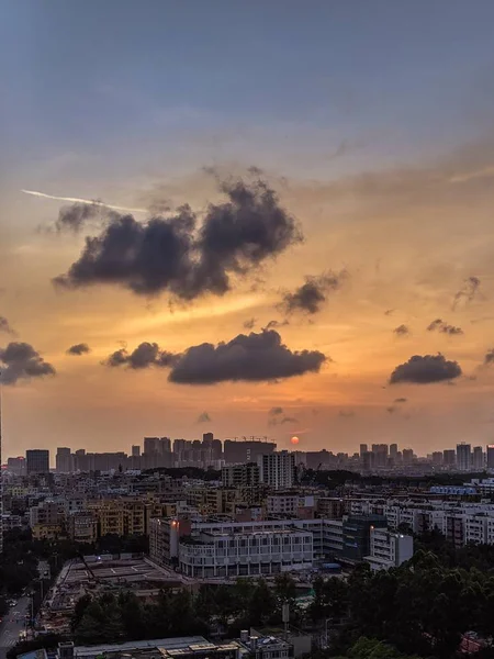 Ampla foto de uma cidade moderna e movimentada com céu escuro e nuvens durante o pôr do sol — Fotografia de Stock