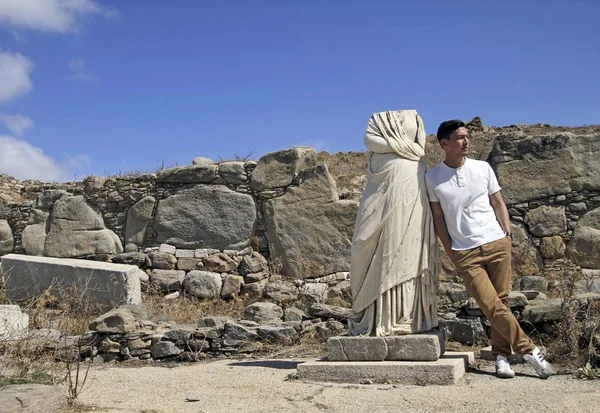 Amplio ángulo de tiro de un hombre junto a una estatua rodeada de piedras —  Fotos de Stock