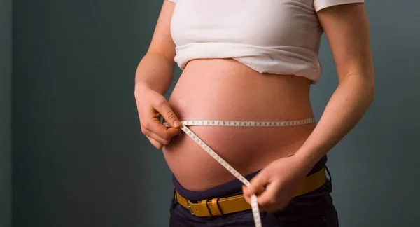 Belo tiro de uma mulher grávida medindo sua barriga — Fotografia de Stock