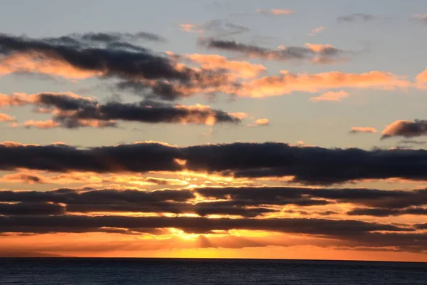 De puesta de sol con rayo de luz solar en un cielo nublado en el océano. —  Fotos de Stock