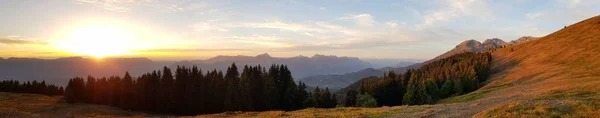 Atemberaubende Panoramaaufnahme von schönen steilen Hügeln und Wäldern mit dem Sonnenaufgang im Hintergrund — Stockfoto