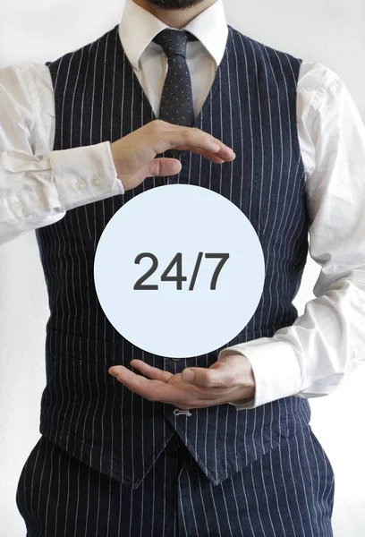 Man with a 24/7 written on a light blue circle in the middle of his hands — Stock Photo, Image