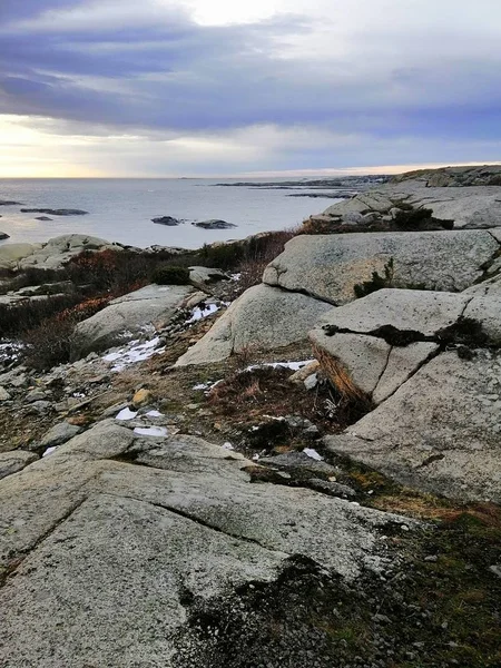 Pionowy obraz skał otoczonych morzem podczas zachodu słońca w Rakke w Norwegii — Zdjęcie stockowe