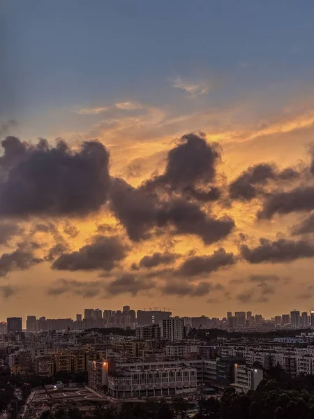 Bred bild av en modern och upptagen stad med en orange himmel och mörka moln — Stockfoto