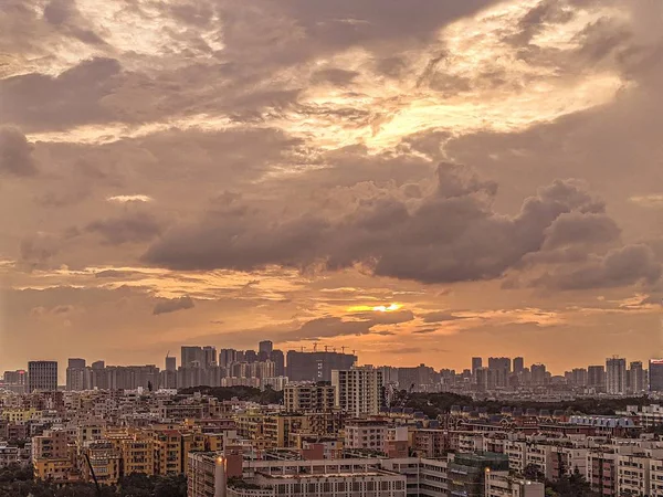 Wide shot of a modern city with a sky and heavy clouds during sunset — Stock Photo, Image