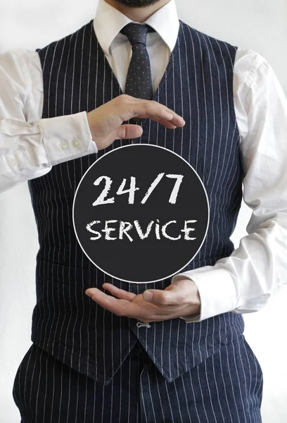 Man met een 24 / 7 servicetekst geschreven op een zwarte cirkel in het midden van zijn handen — Stockfoto