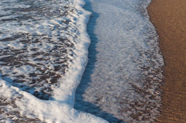 Vysoký úhel záběru pěnivé oceánské vody přijíždějící na písčité pobřeží — Stock fotografie