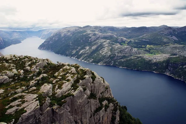 Schöne Landschaft der berühmten Preikestolen Klippen in der Nähe eines Sees unter wolkenverhangenem Himmel in Stavanger, Norwegen — Stockfoto