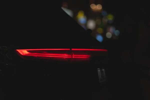 Luxury car rear at illuminated dark night scene in downtown munich. Red breaking light in city — Stock Photo, Image