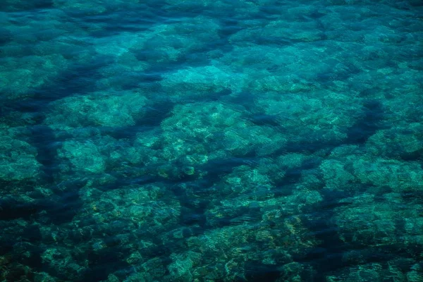 Brede hoekopname van de stenen onder de oceaan gezien door het transparante water — Stockfoto