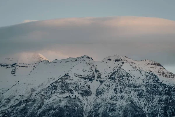 Alta angolazione delle montagne coperte di neve sotto il cielo nuvoloso del tramonto — Foto Stock