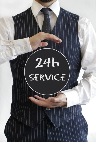 Homem com um texto de serviço 24h escrito em um círculo negro no meio de suas mãos — Fotografia de Stock