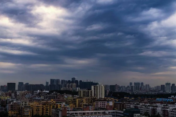 Vistas a una ciudad moderna y concurrida con cielo azul oscuro y nubes —  Fotos de Stock